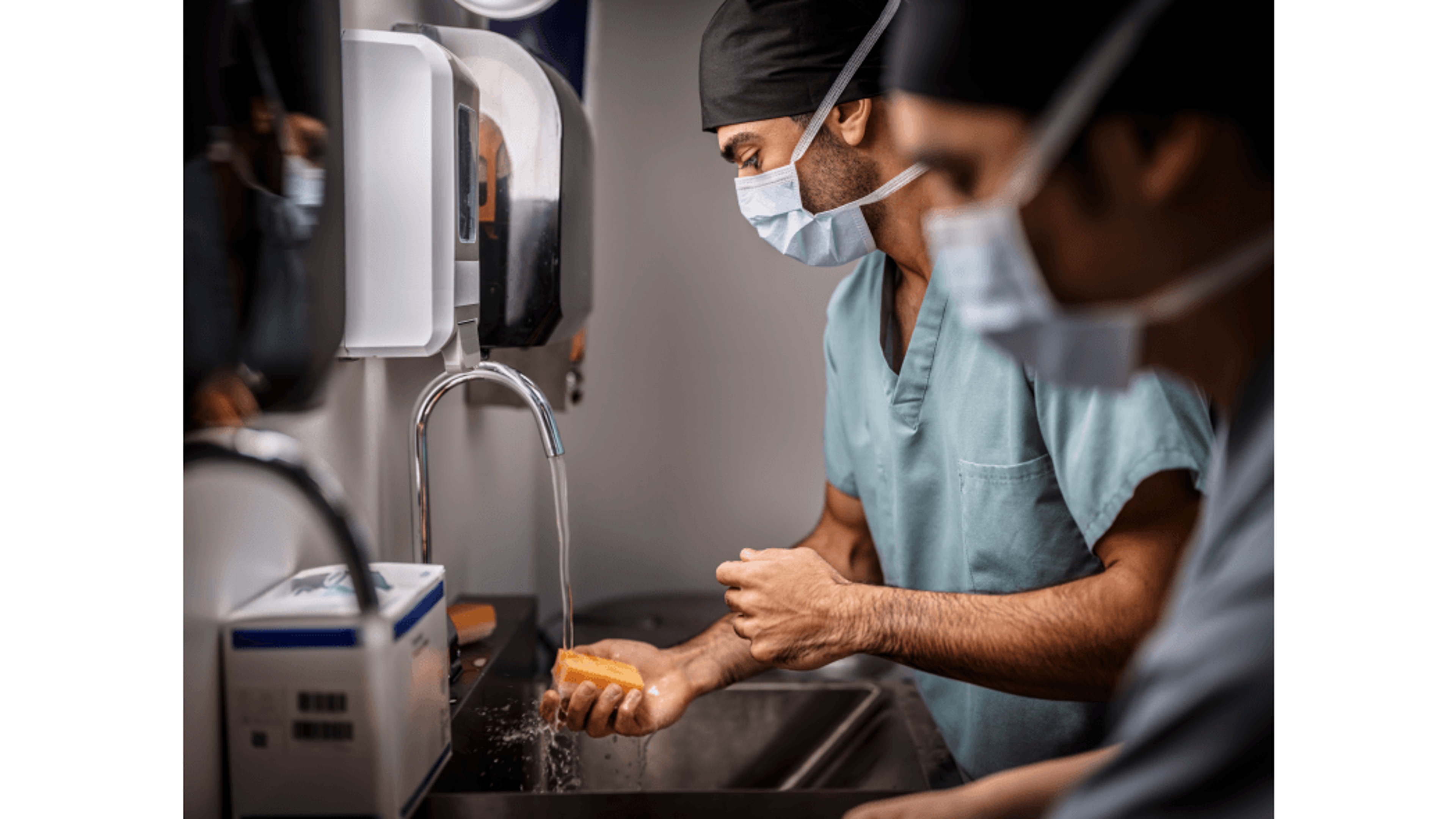 Two surgeons in masks and scrubs washing their hands