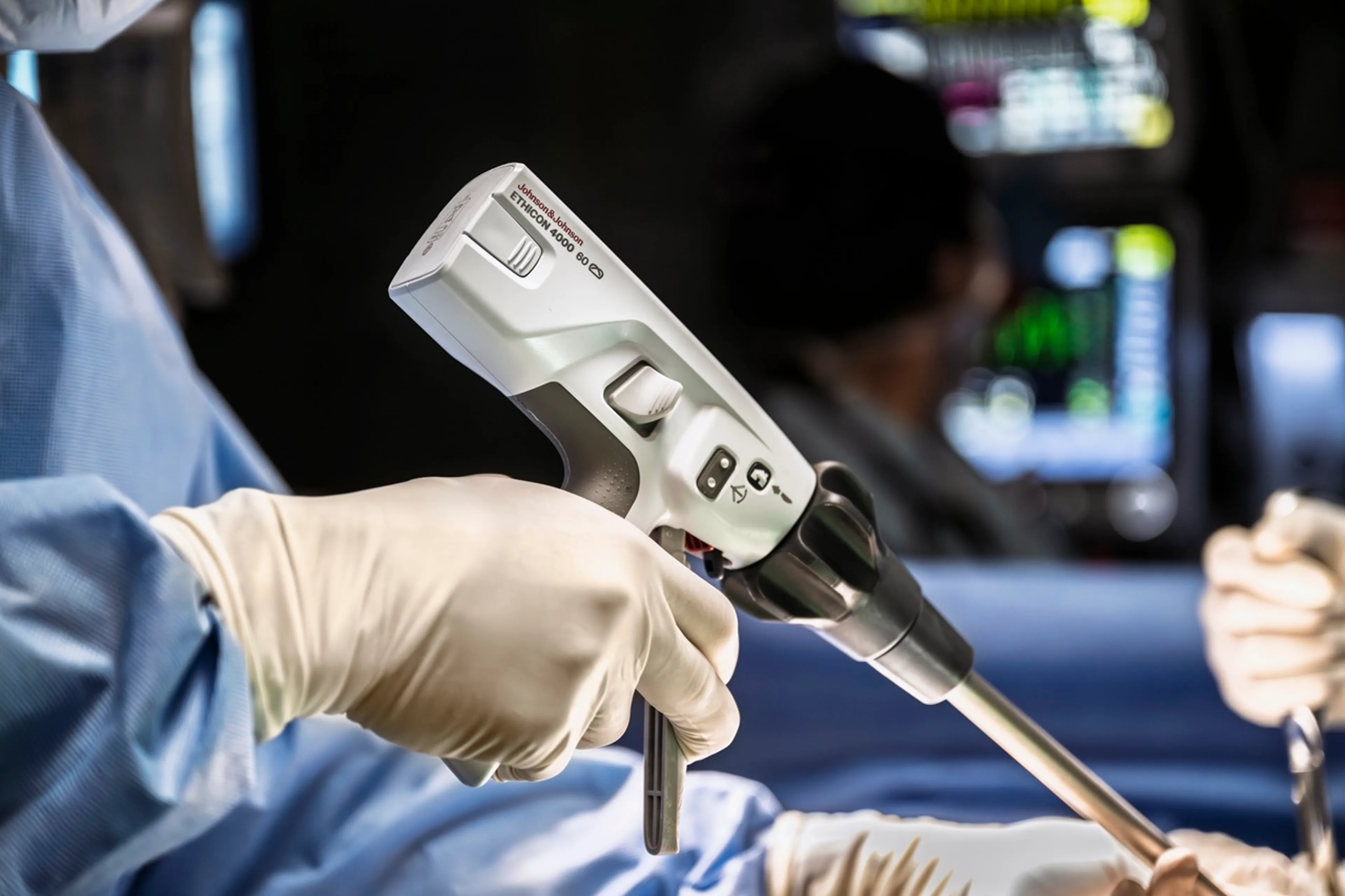 A close-up of a surgeon wearing gloves and using a surgical stapler