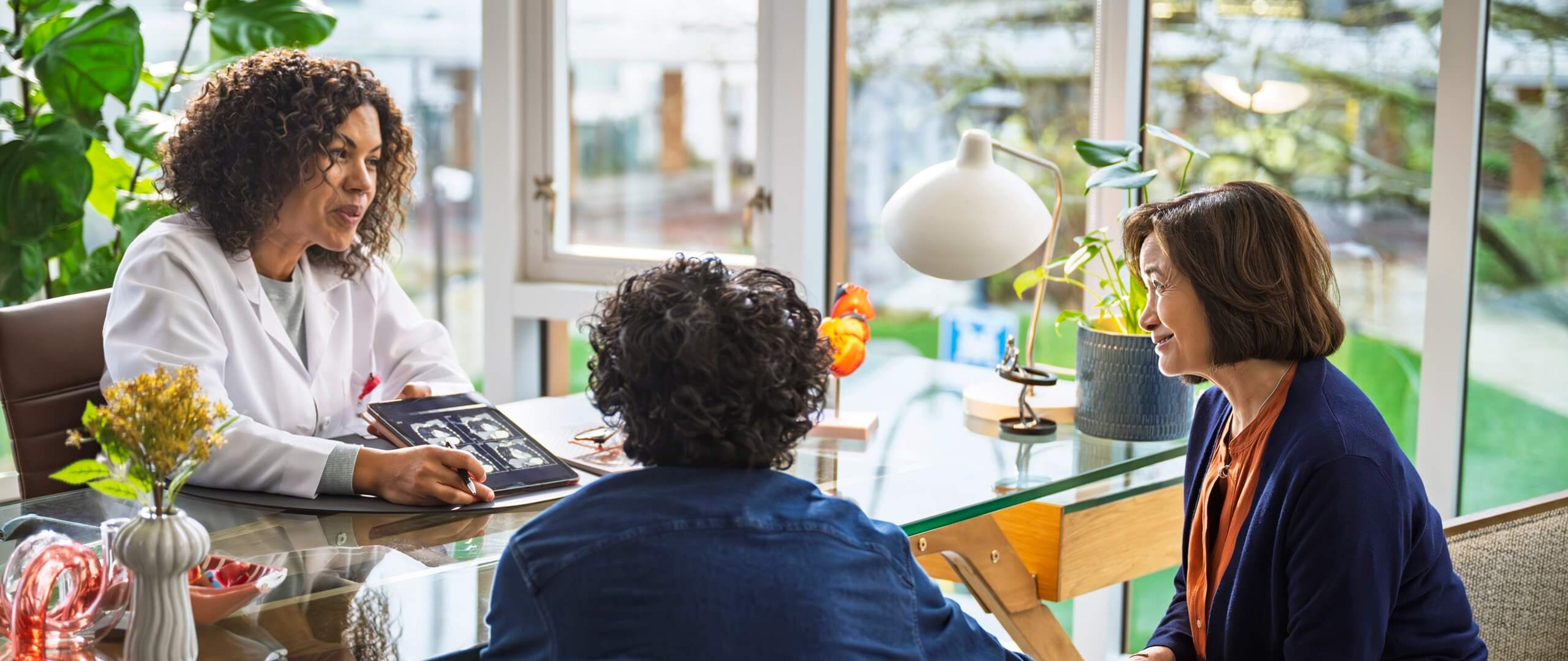 Patient meeting with a cardiologist during a consultation, accompanied by a loved one in a bright, comfortable office.