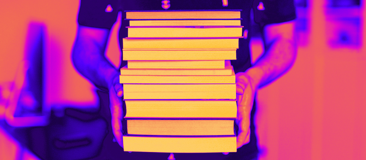 Photograph of a person holding a stack of print books with neon photo filter. 