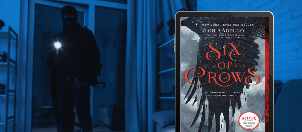 A thief holds a flashlight in a dark room. A phone displays the book "Six of Crows."
