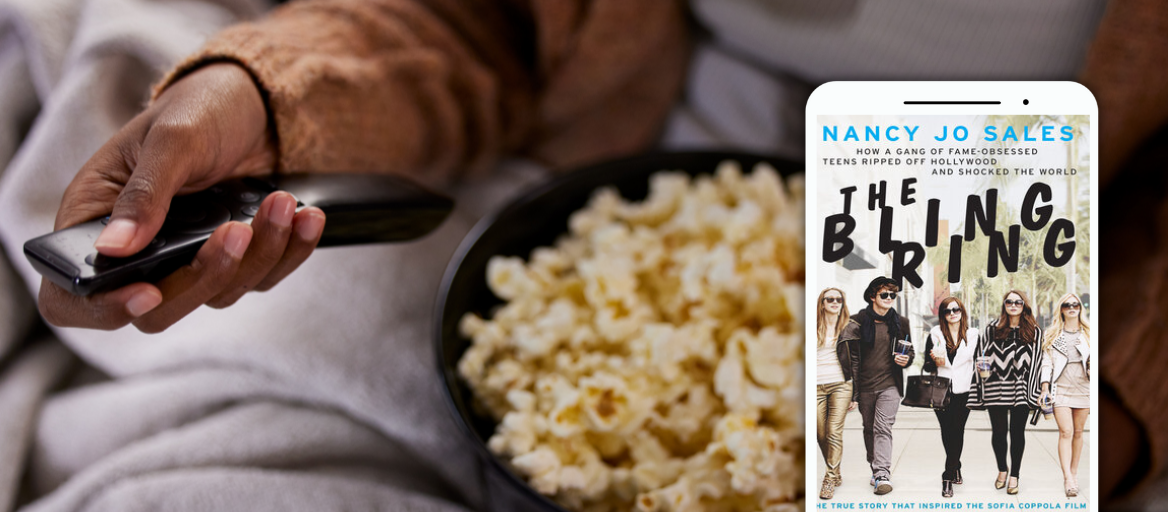 A person sits on a couch with a bowl of popcorn and a remote control in their hand. To the right is a tablet featuring the ebook "The Bling Ring."