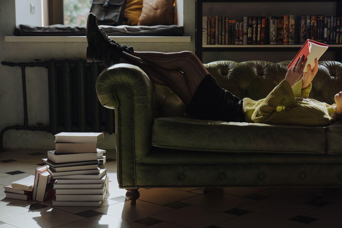 Person relaxing on a couch reading a book