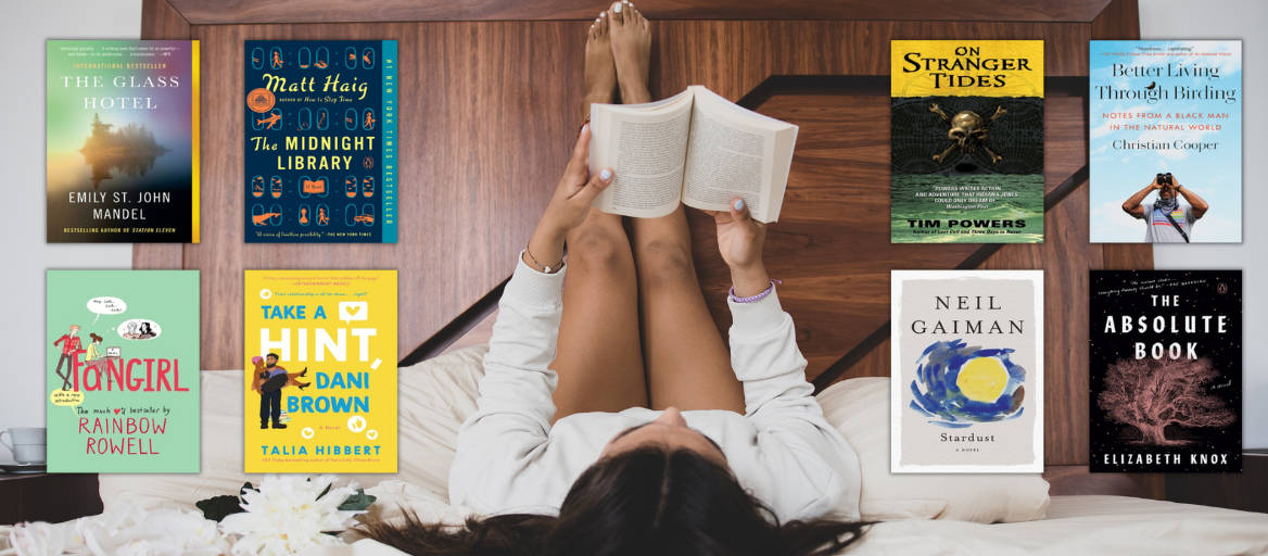 A woman relaxes in bed with her legs propped up reading a book. Book covers are featured on both sides of the woman.