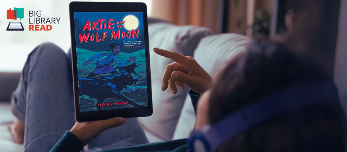 A person lays on a couch with headphones while holding a tablet with the ebook "Artie and the Wolf Moon."