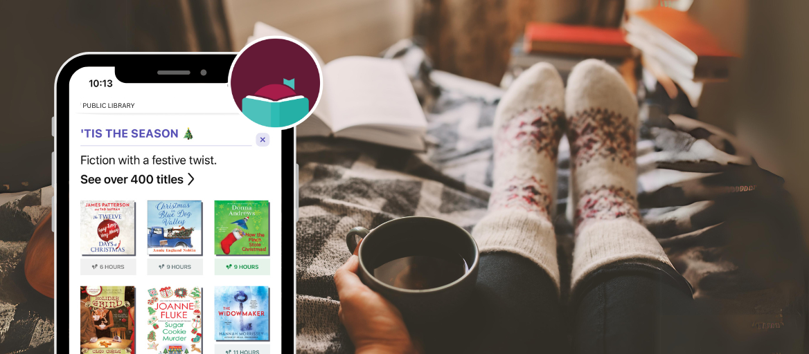 A person sitting on a bed with a cup of coffee and a book. A phone features the a collection of holiday books on the Libby app. 