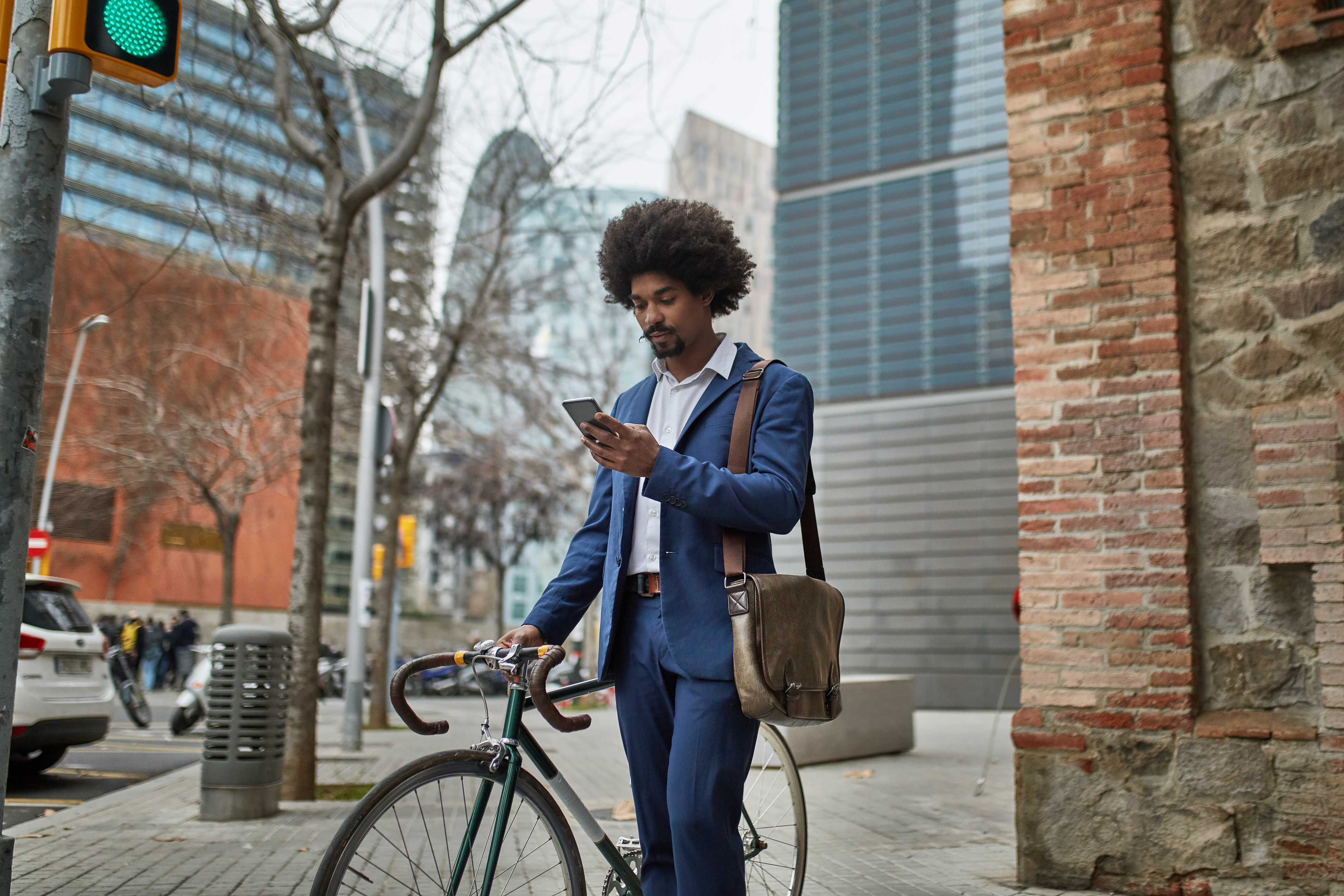 Young man with his bike, checking his phone in a campus.