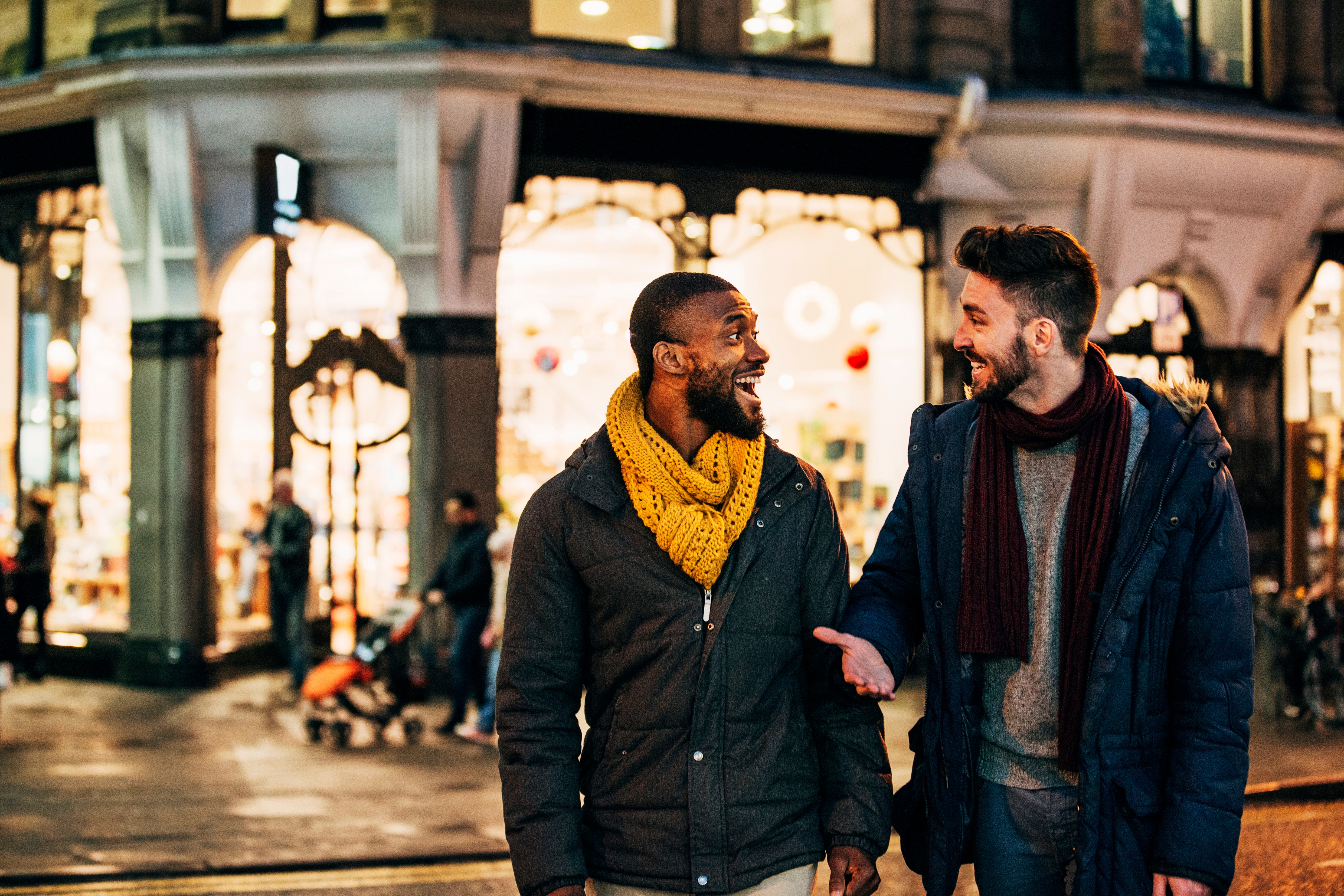 Two friends talking while walking in the street at night.