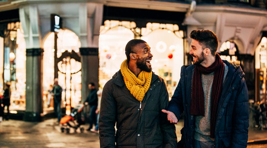 Two friends talking while walking in the street at night.