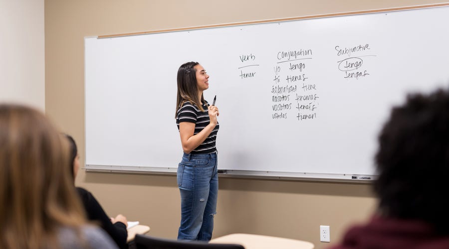 Student practicing a language exercise in front of the class.
