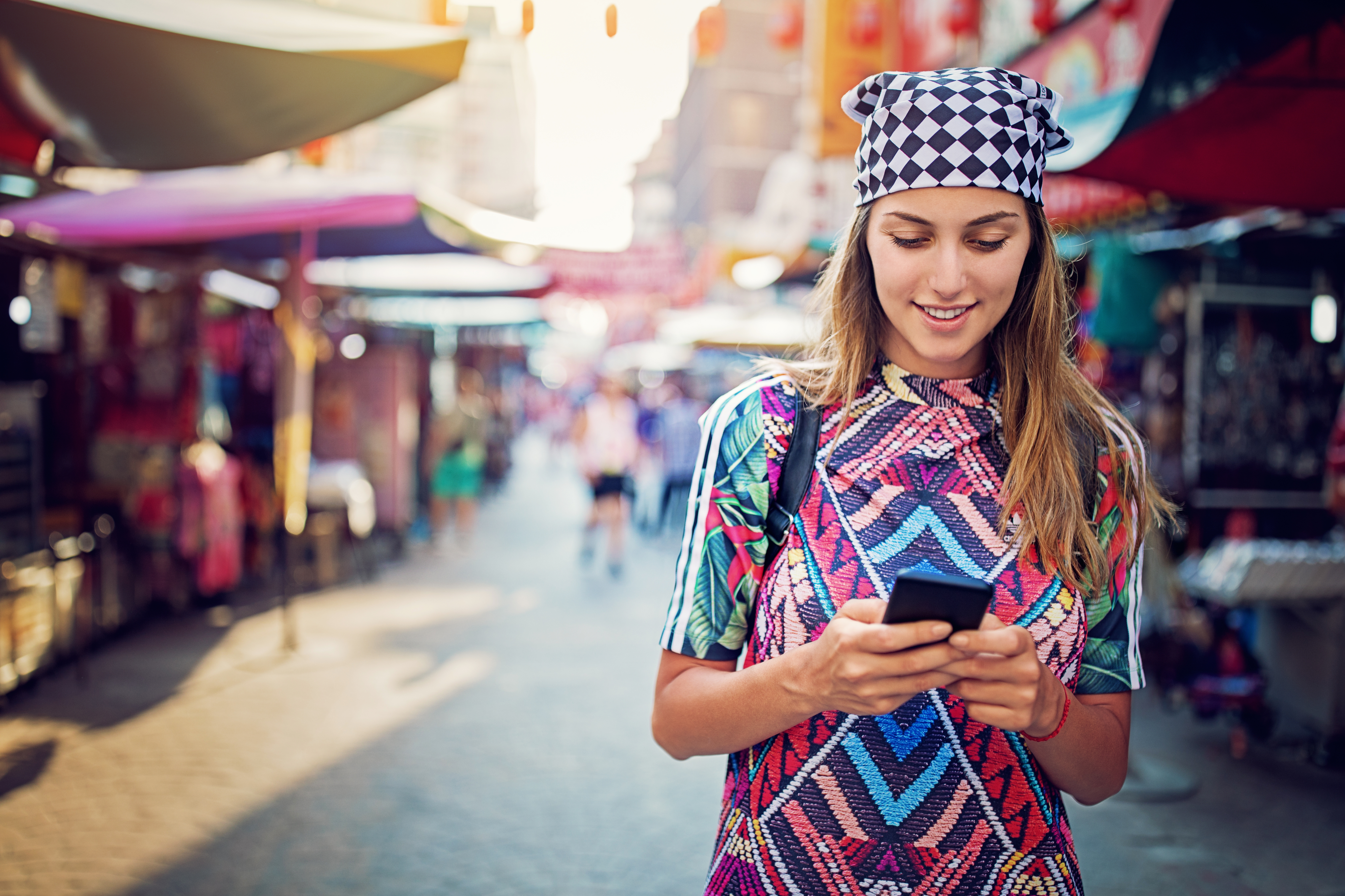 Girl chatting on her phone while walking on the street.