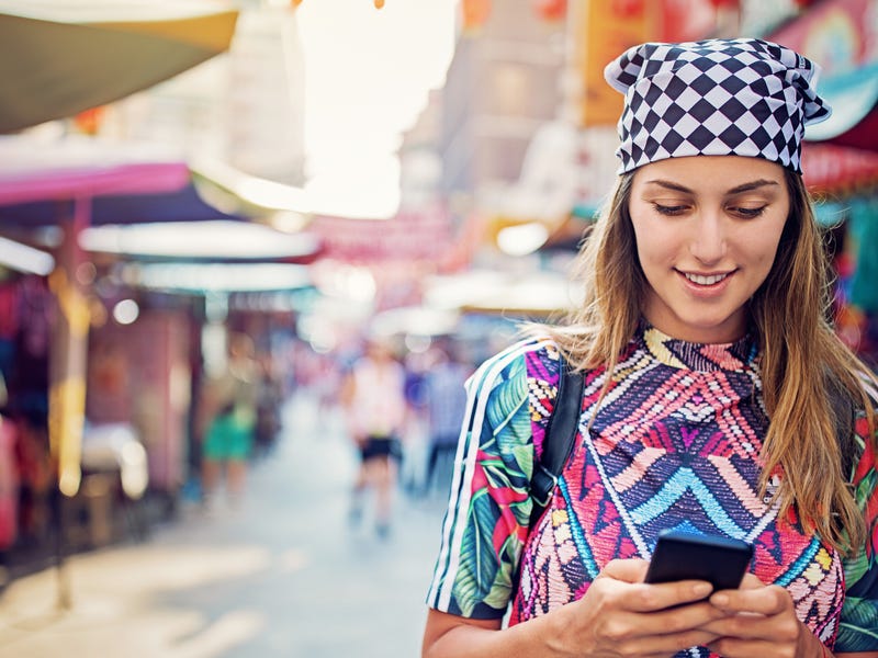 Girl chatting on her phone while walking on the street.