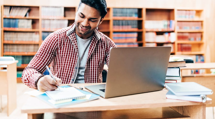 Man learning English online while taking notes.