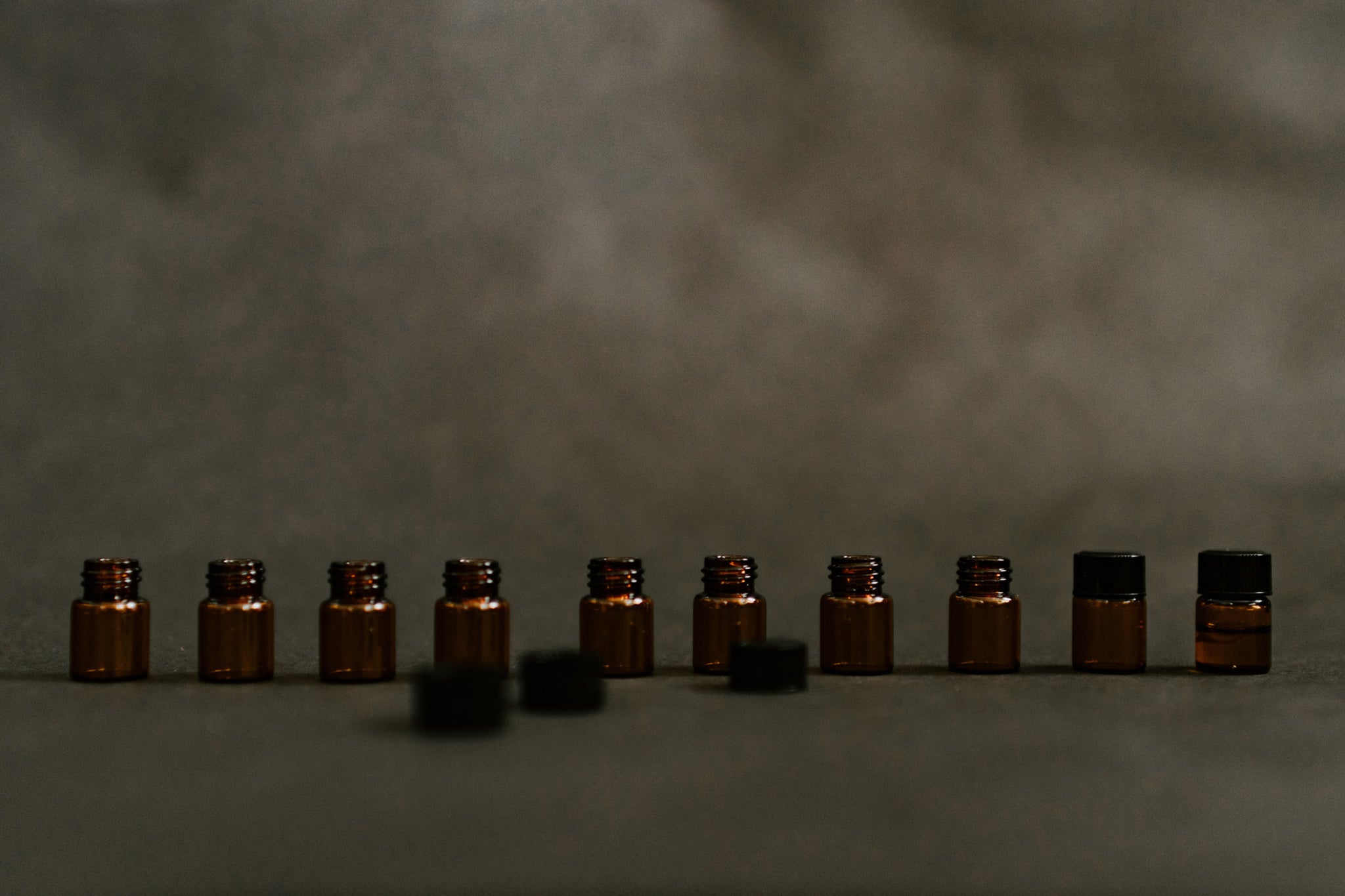 ten essential oils in brown bottles on table smoky brown background