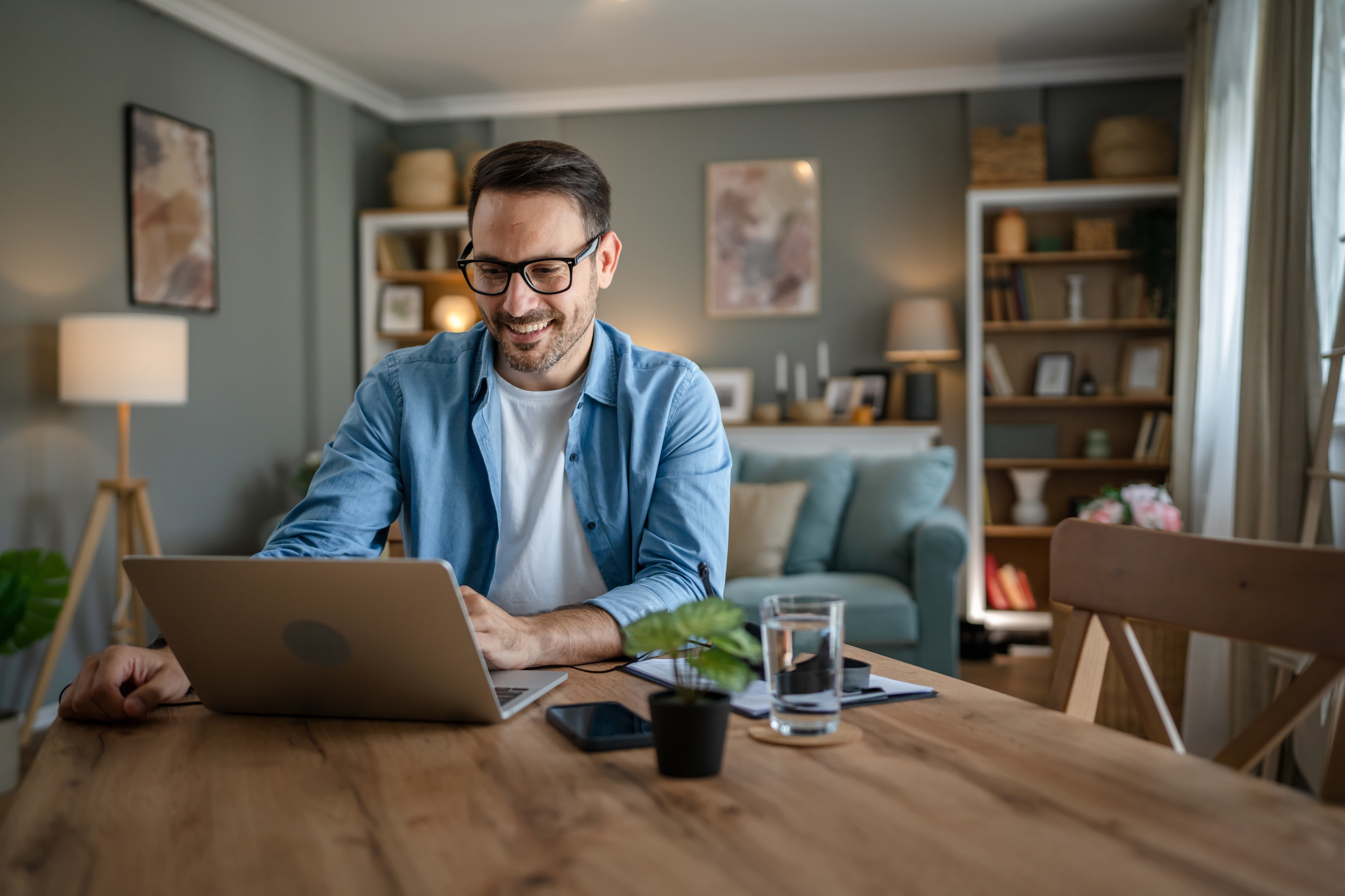 Man sitting at a table in his living room and looking for online language courses on his laptop