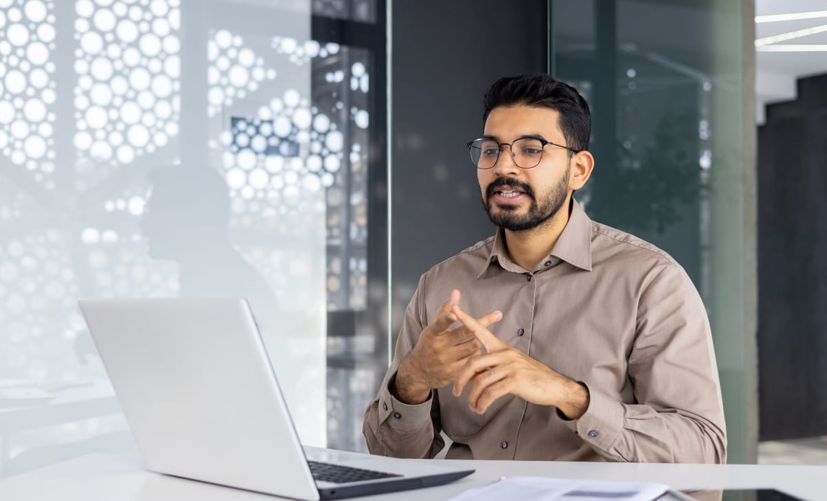 Man sitting in front of a laptop and talking to his instructor during a German online training