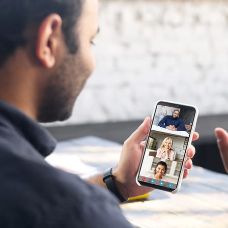 Student greeting his classmates in an online group lesson while holding up his phone