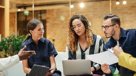Team of employees sitting on a couch and discussing signing up for soft skills seminars with Berlitz