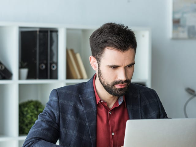 Businessman in his office sitting at his desk and learning a language with Berlitz's On Demand self-study course