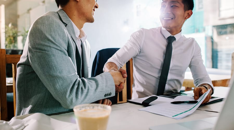 Two businessmen shaking hands and thanking each other for coming to a meeting
