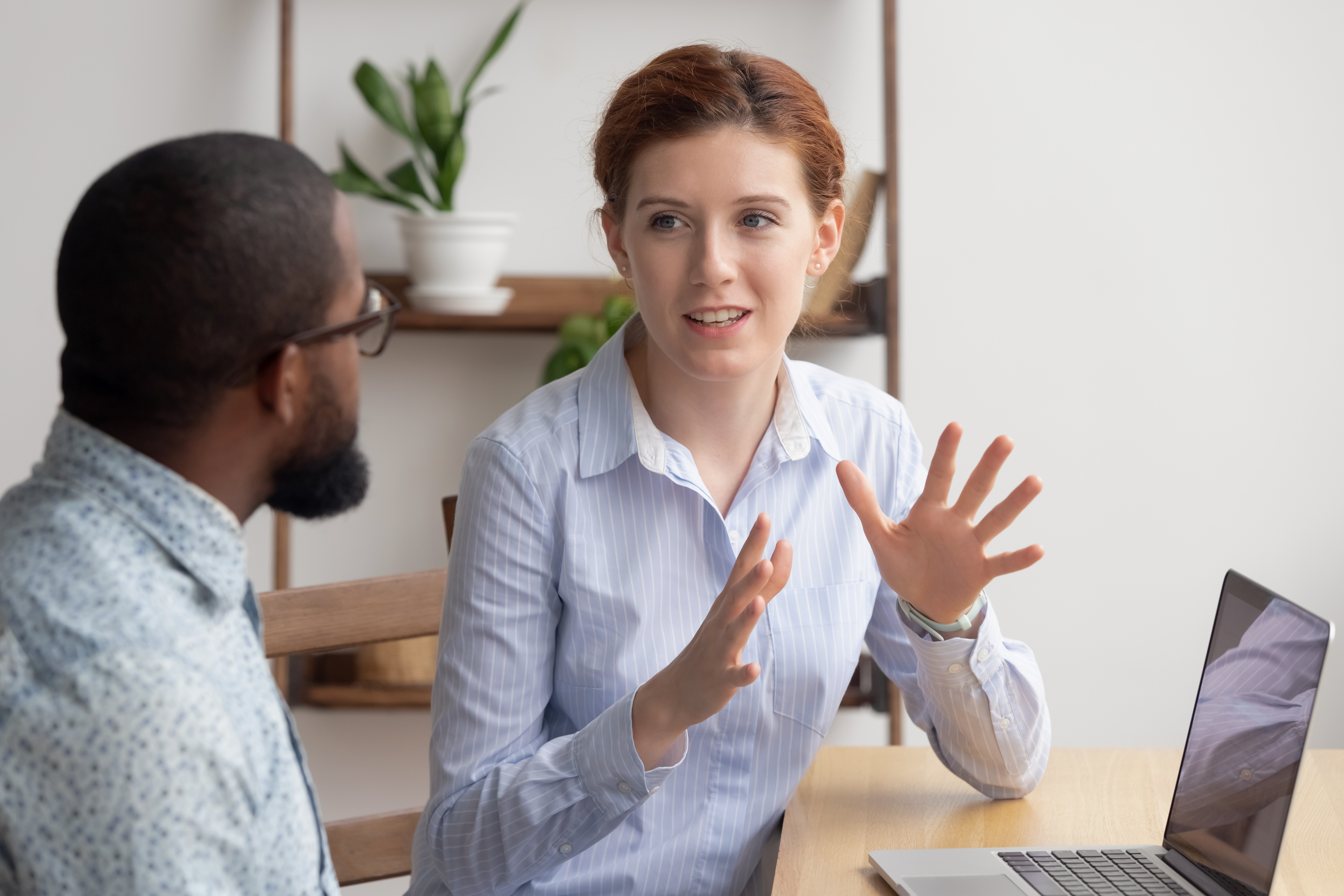 Instructor sitting next to her student and talking to him in a foreign language to prepare him for a language proficiency test