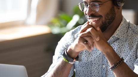 Man in headphones sitting in front of his laptop and learning a new language with Berlitz Flex
