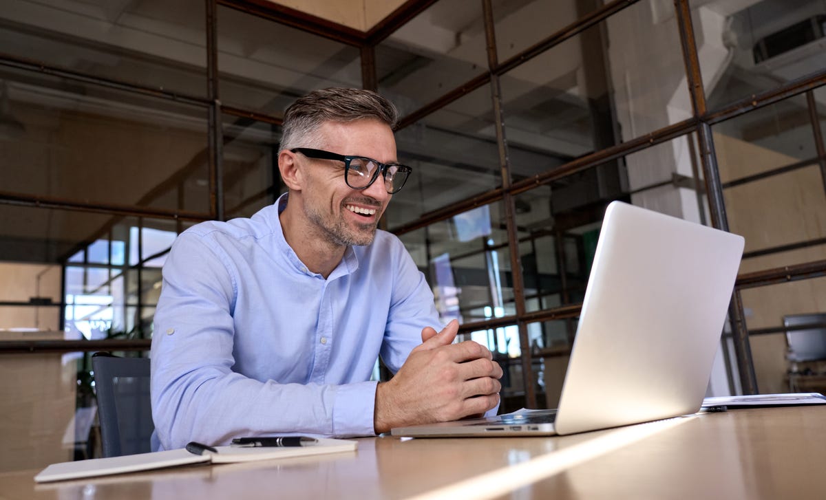 Businessman in his office sitting at his desk and learning a language with Berlitz's On Demand self-study course