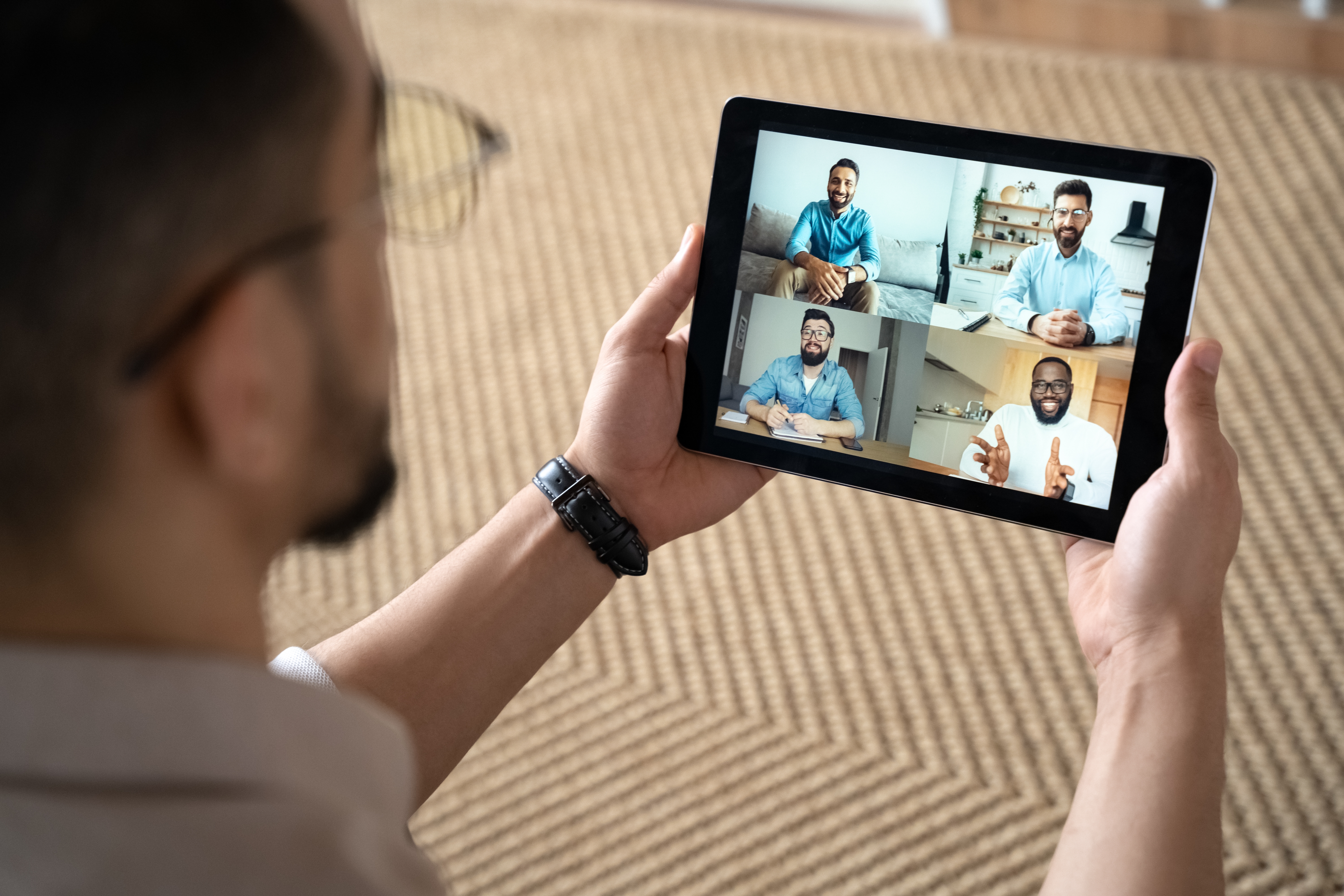 Man holding a tablet and attending an online group class with Berlitz