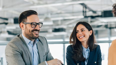 Two team leaders learn Business English and talk to their instructor who is sitting across the table
