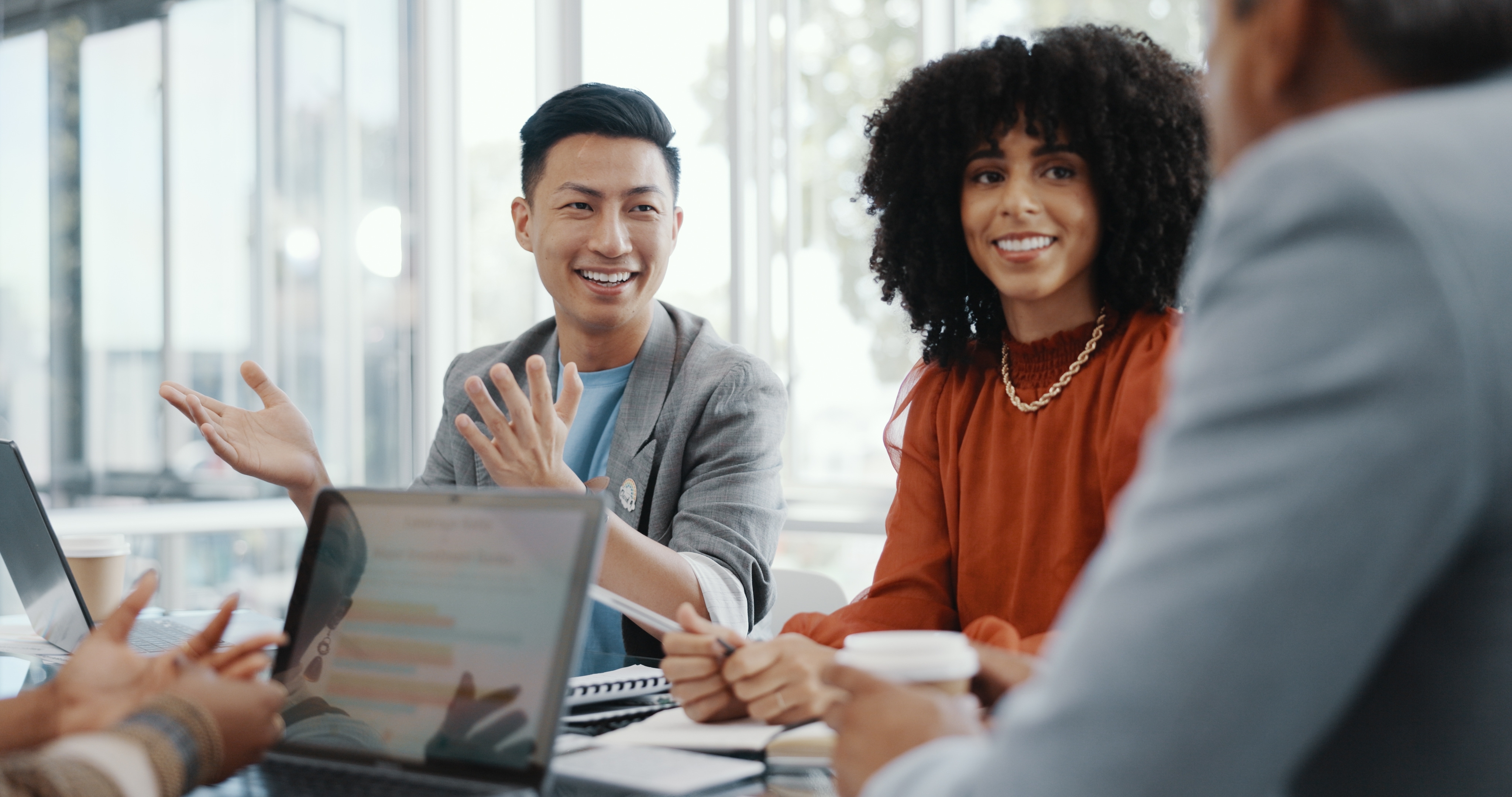 Man and woman in their workplace talking to their instructor and smiling during a cross-cultural training