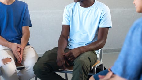 Teenagers sitting in a circle in front of a note board and talking to each other and their instructor during a lesson with Berlitz where they learn Spanish for kids and teens