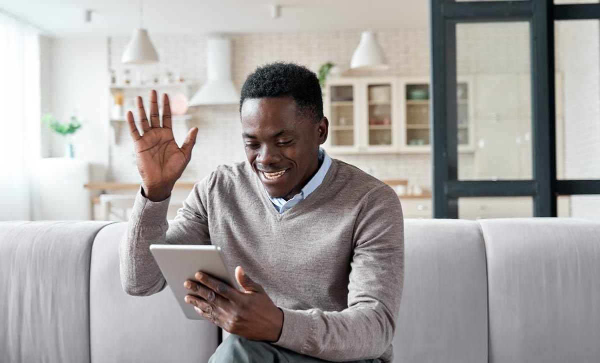 Man saying hi to his instructor before his online French lesson that he is attending from a tablet begins