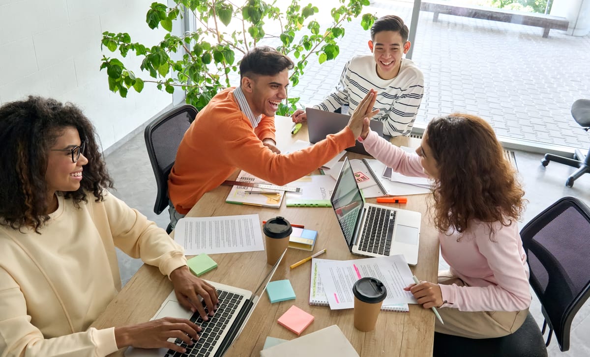 Team members learning Business English with Berlitz and giving each other a high five above the table