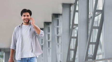 Man at the airport with a suitcase talking on his phone