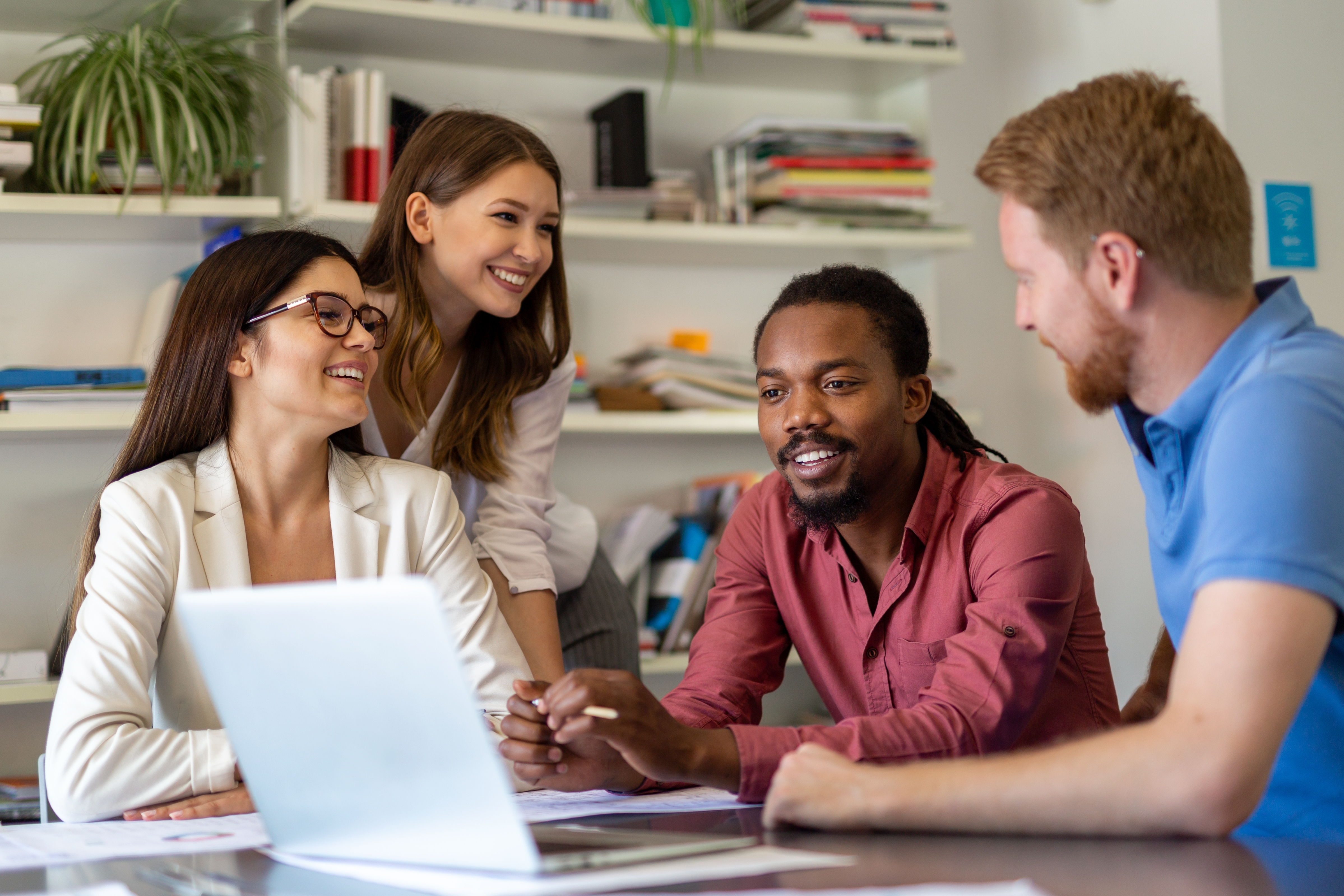 Group of students sit around a laptop and learn a new language with the Berlitz Method