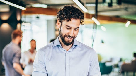 Man in his office holding a tablet and taking an online self-paced language course with Berlitz