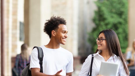 Twi teenagers holding notes and talking to each other while smiling after their French courses for kids and teens
