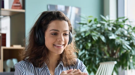 Woman in headphones learning a language with Berlitz Flex and looking at her computer