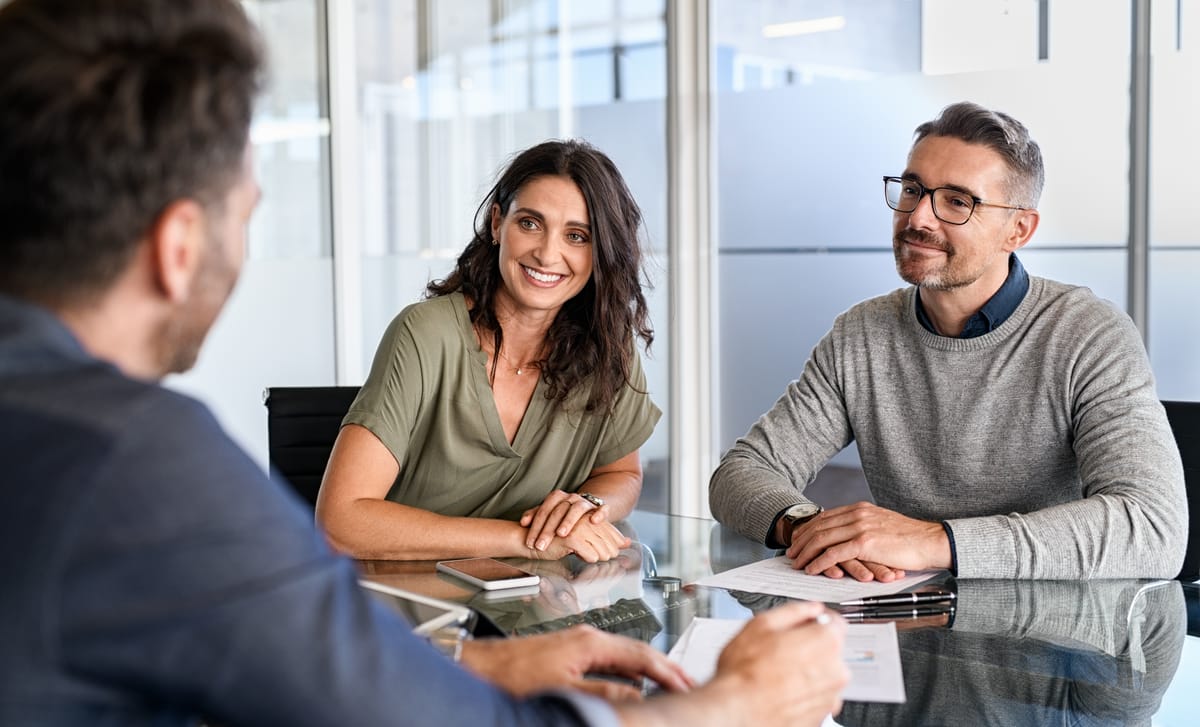 Two students in their workplace sitting at a table listening to their instructor and learning German for professionals