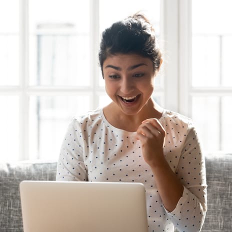 Woman in front of a laptop celebrating her milestones in Berlitz Flex