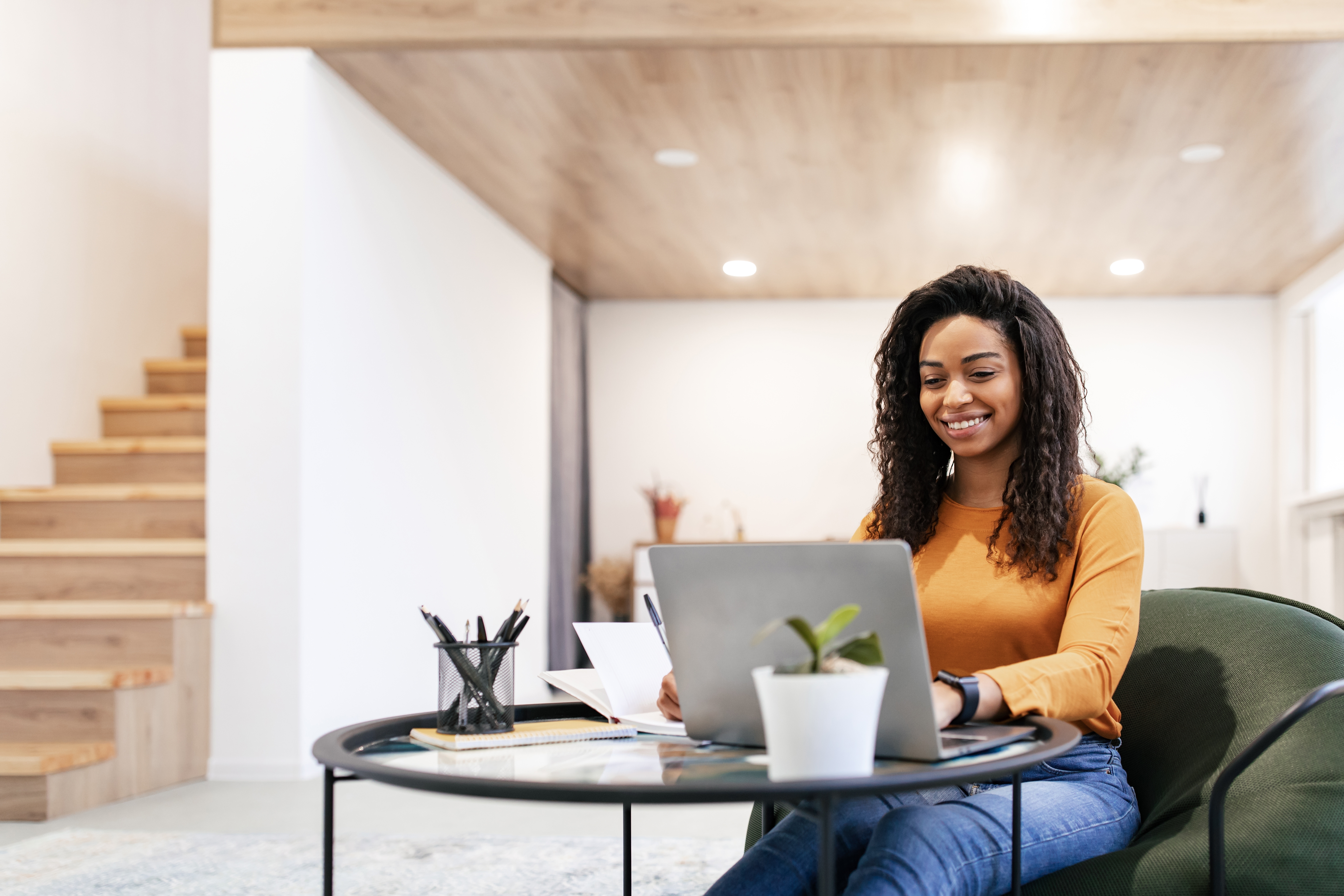 Woman making notes and smiling while learning a language with Berlitz's self-paced online course