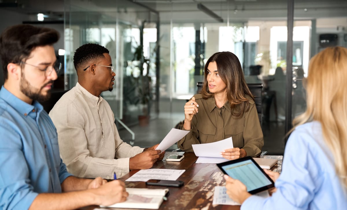 Coworkers sitting around a table with papers and attending a business seminar with Berlitz to improve their skills