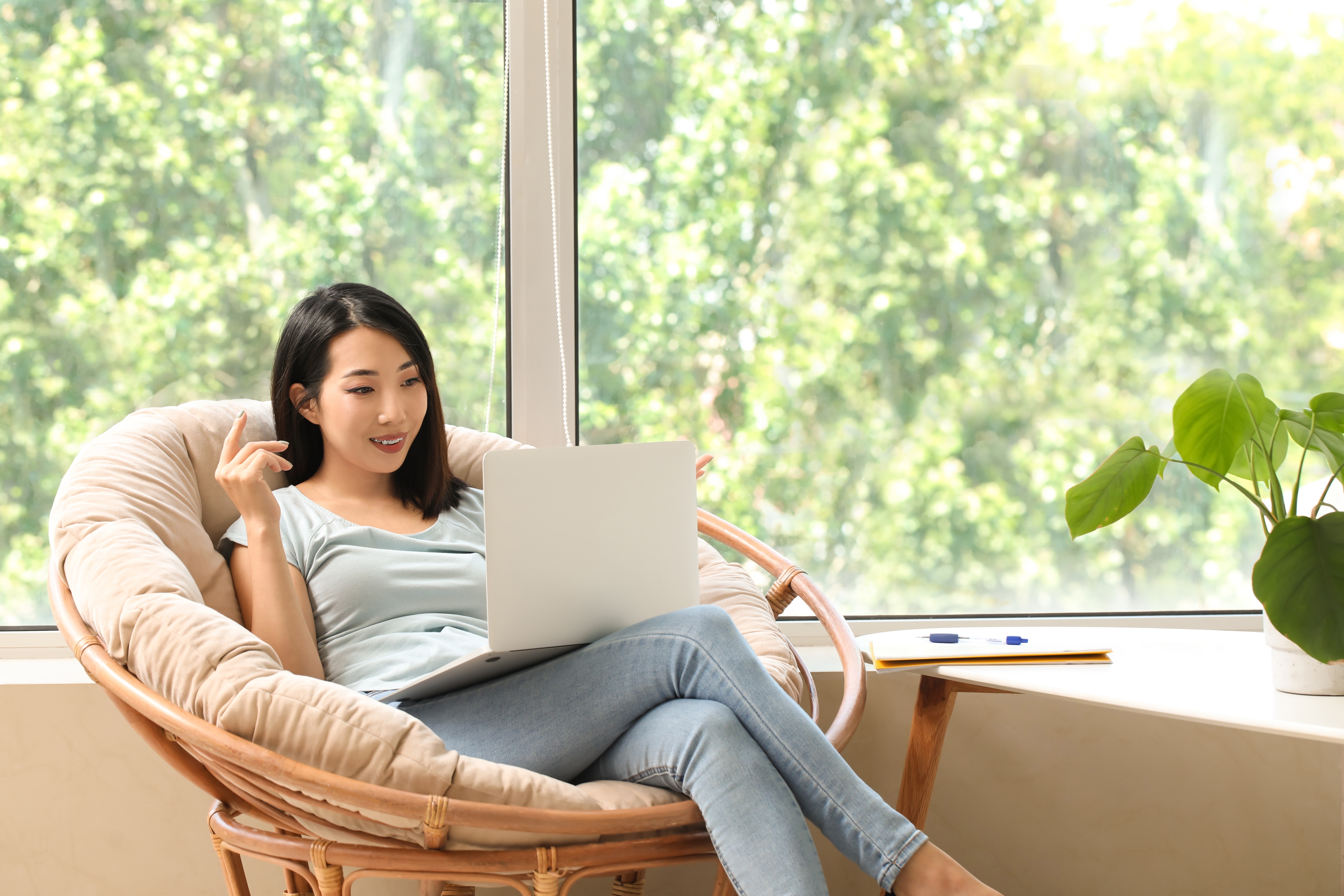 Woman sitting in an armchair and reading about the history of Berlitz on her laptop