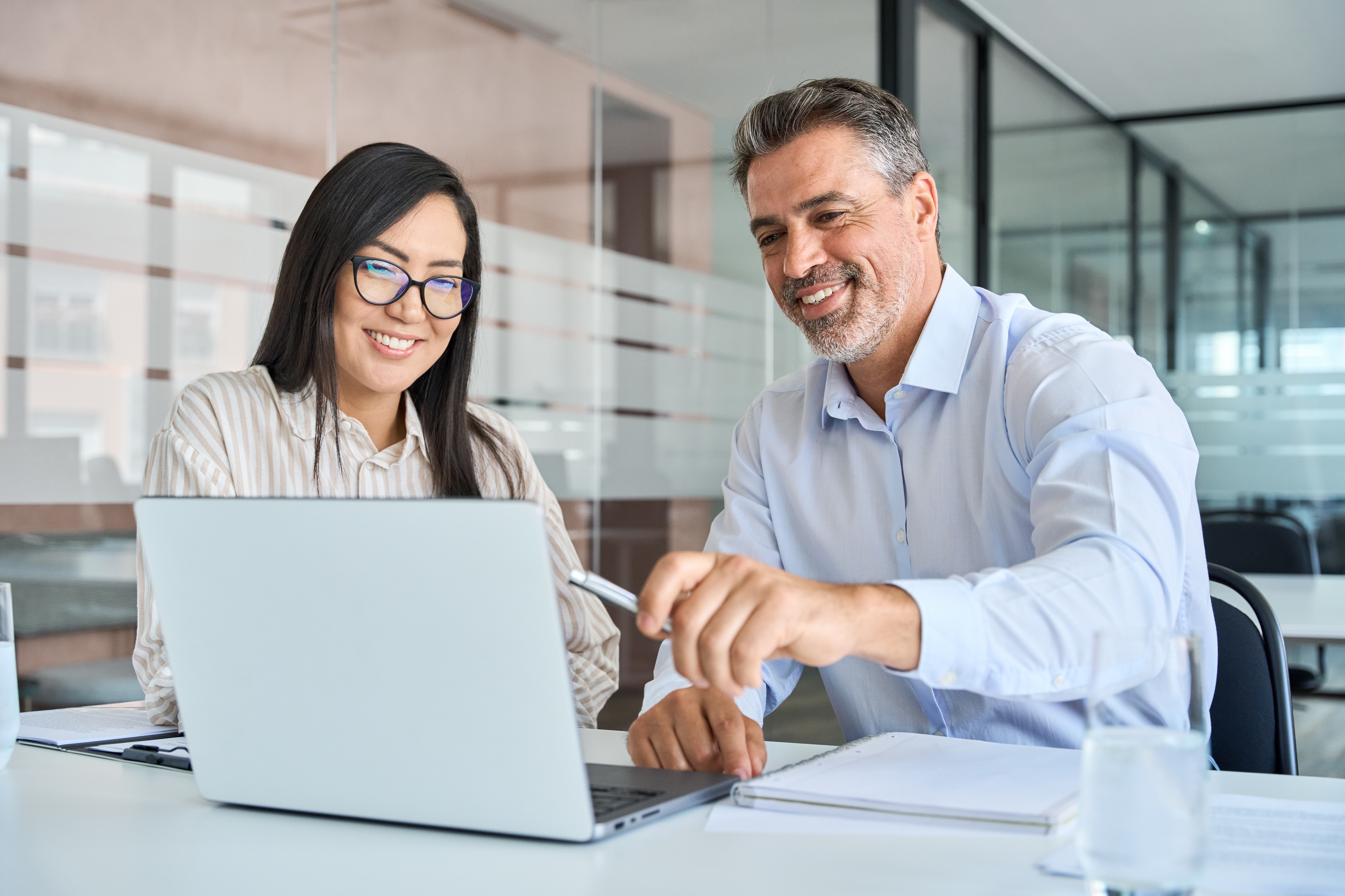 Leader in front of a laptop sharing business materials that were translated to other languages by Berlitz's translation services with his team member