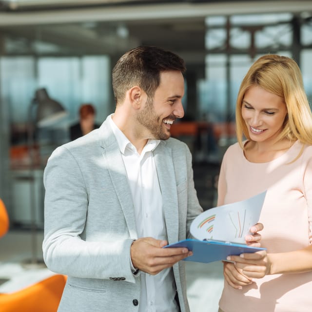 Woman using the language skills she acquired during private language lessons in her work life and checking a document with a coworker