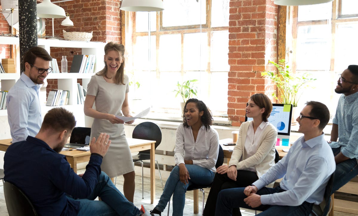Employees sitting in a circle and talking to each other and their instructor during a language training for companies
