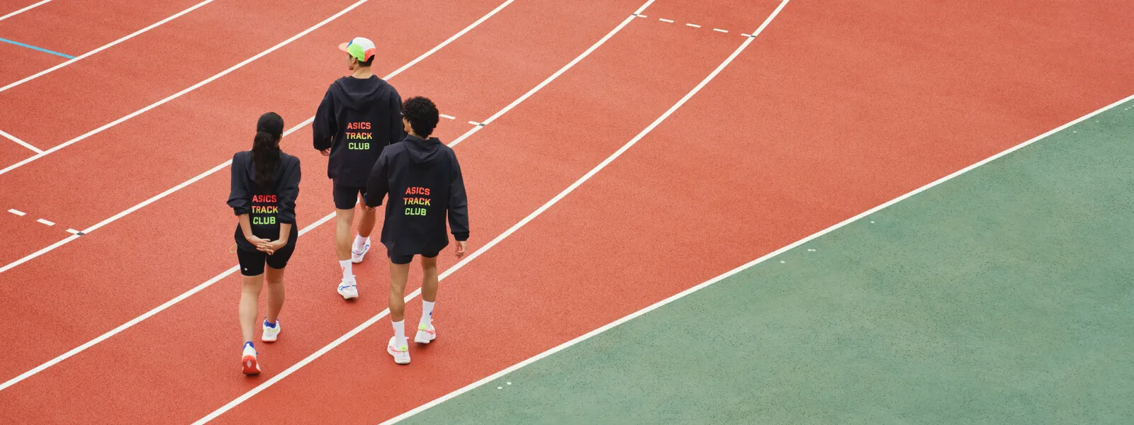 Three people walking on a running track wearing ASICS clothing and shoes