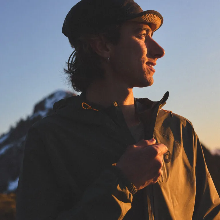 Man wearing trail clothing and standing in front of blue background