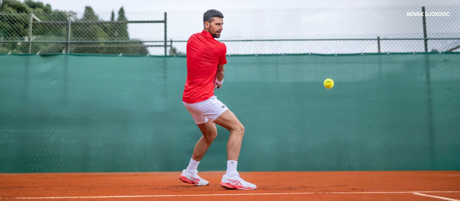 Novak Djokovic playing tennis in red shirt and ASICS shoes