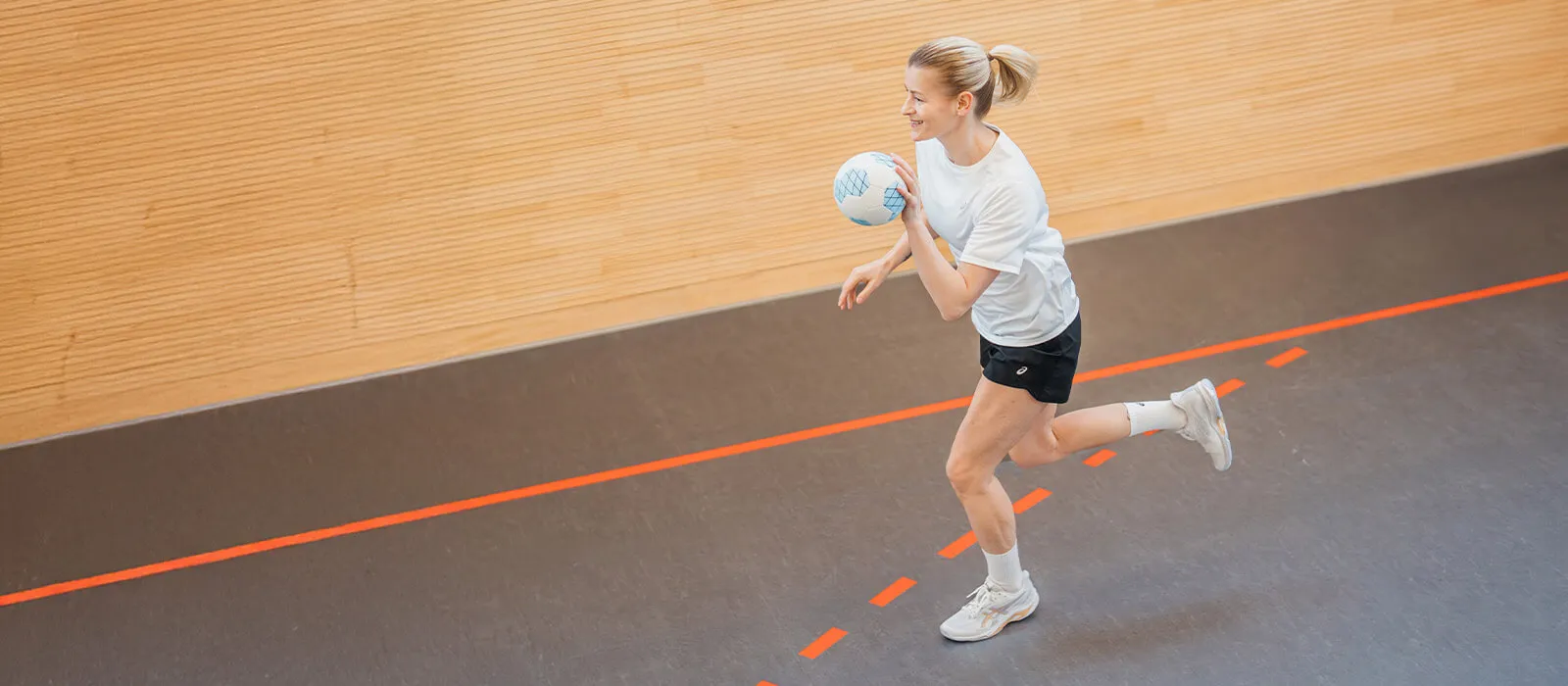 Woman playing handball in blue ASICS shoes